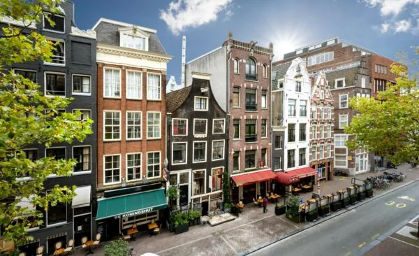 Rij historische grachtenpanden met cafés en restaurants aan de Nieuwezijds Voorburgwal in Amsterdam.